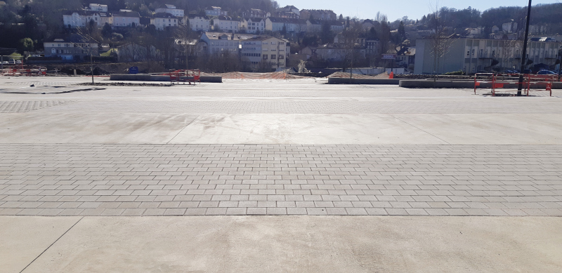 Illustration - De grandes bandes de béton couleur tabac et de pavés béton s’alternent au sol